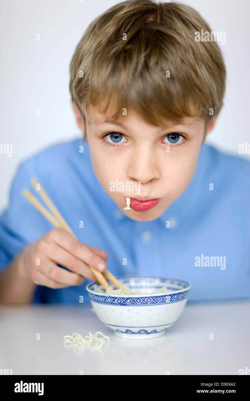 Portrait of boy eating noodles with chopsticks Stock Photo Alamy