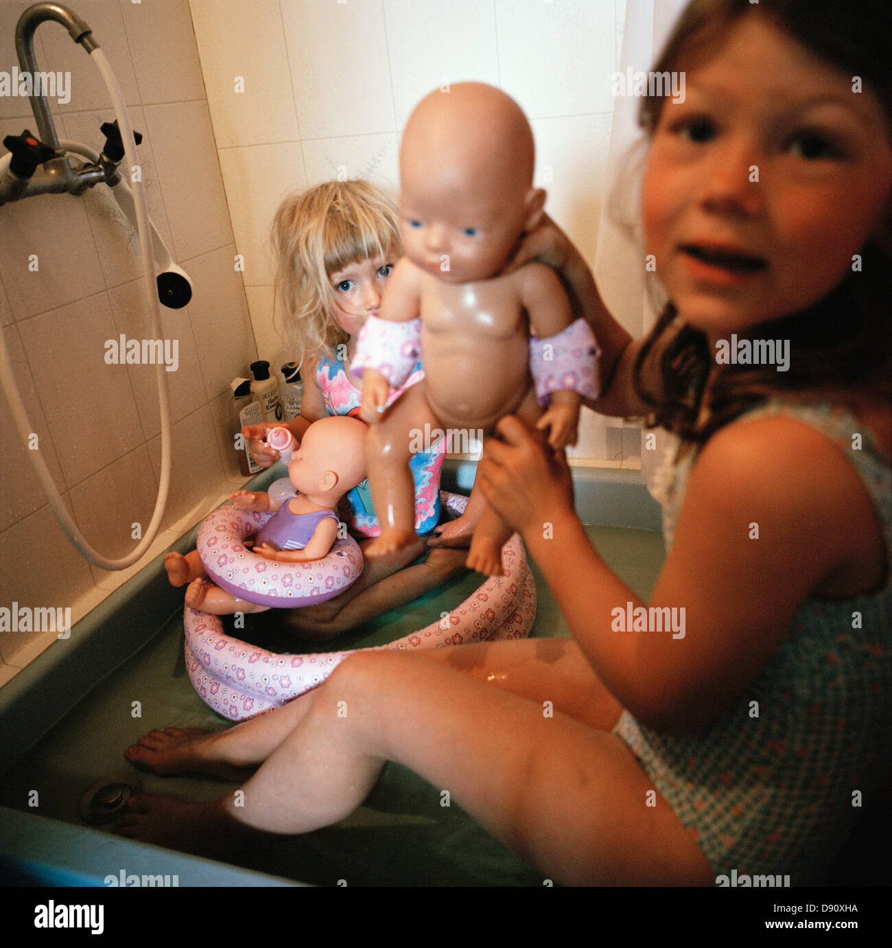 Two girls playing with dolls in a bathroom, Sweden. Stock Photo