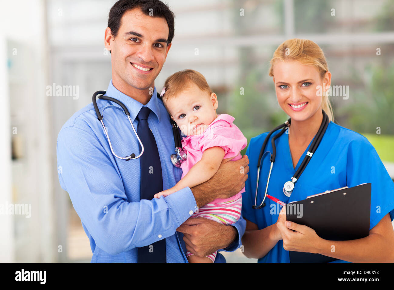 smiling pediatric doctor and nurse with baby girl Stock Photo