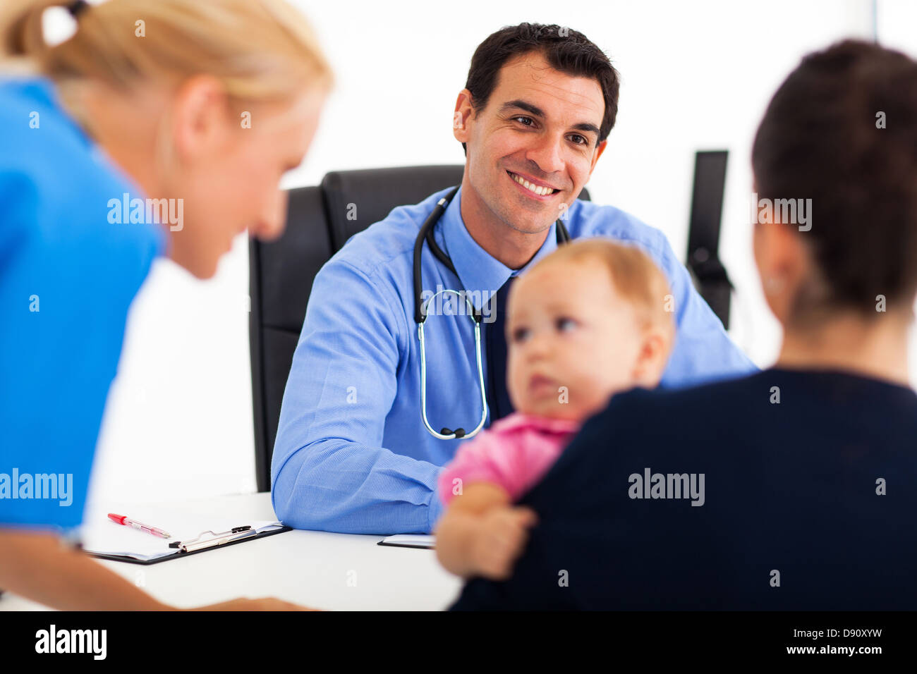 pediatric doctor talking to baby patient's mother while nurse playing