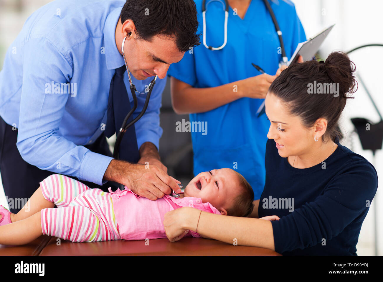 pediatric doctor examining a criying baby in clinic Stock Photo