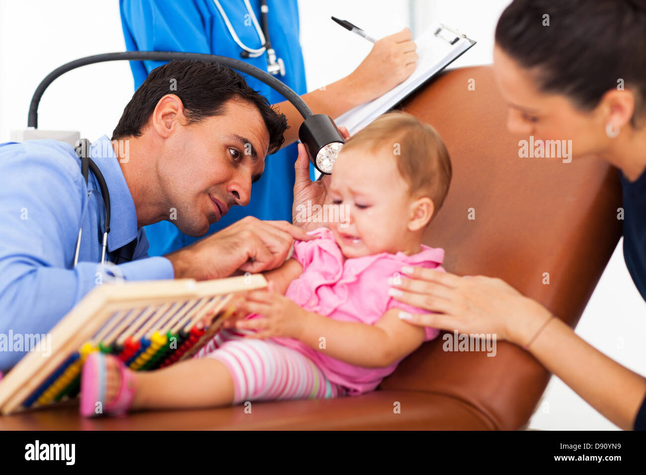 peadiatric doctor examining a sick baby's ear in office Stock Photo