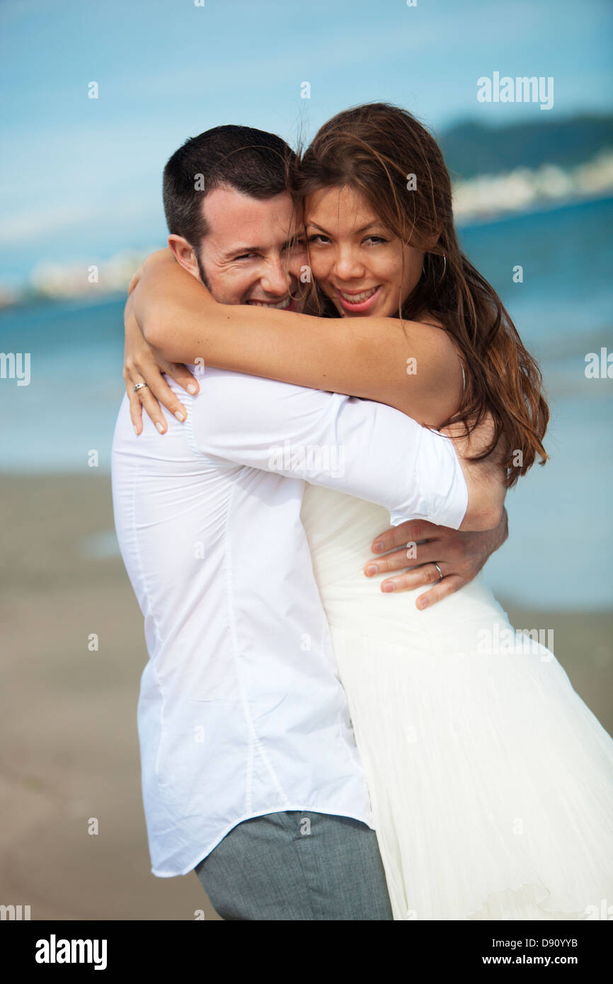 Newlyweds embracing on beach Stock Photo