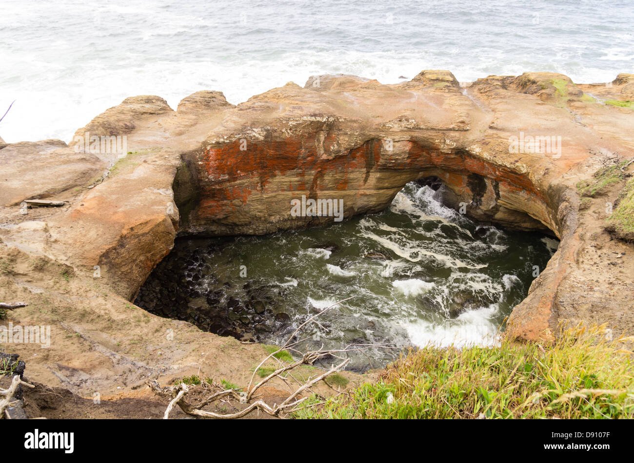 Oregon, Otter Rock, Devils Punch Bowl State Park. Water washes through Devil's Punchbowl rock formation Stock Photo