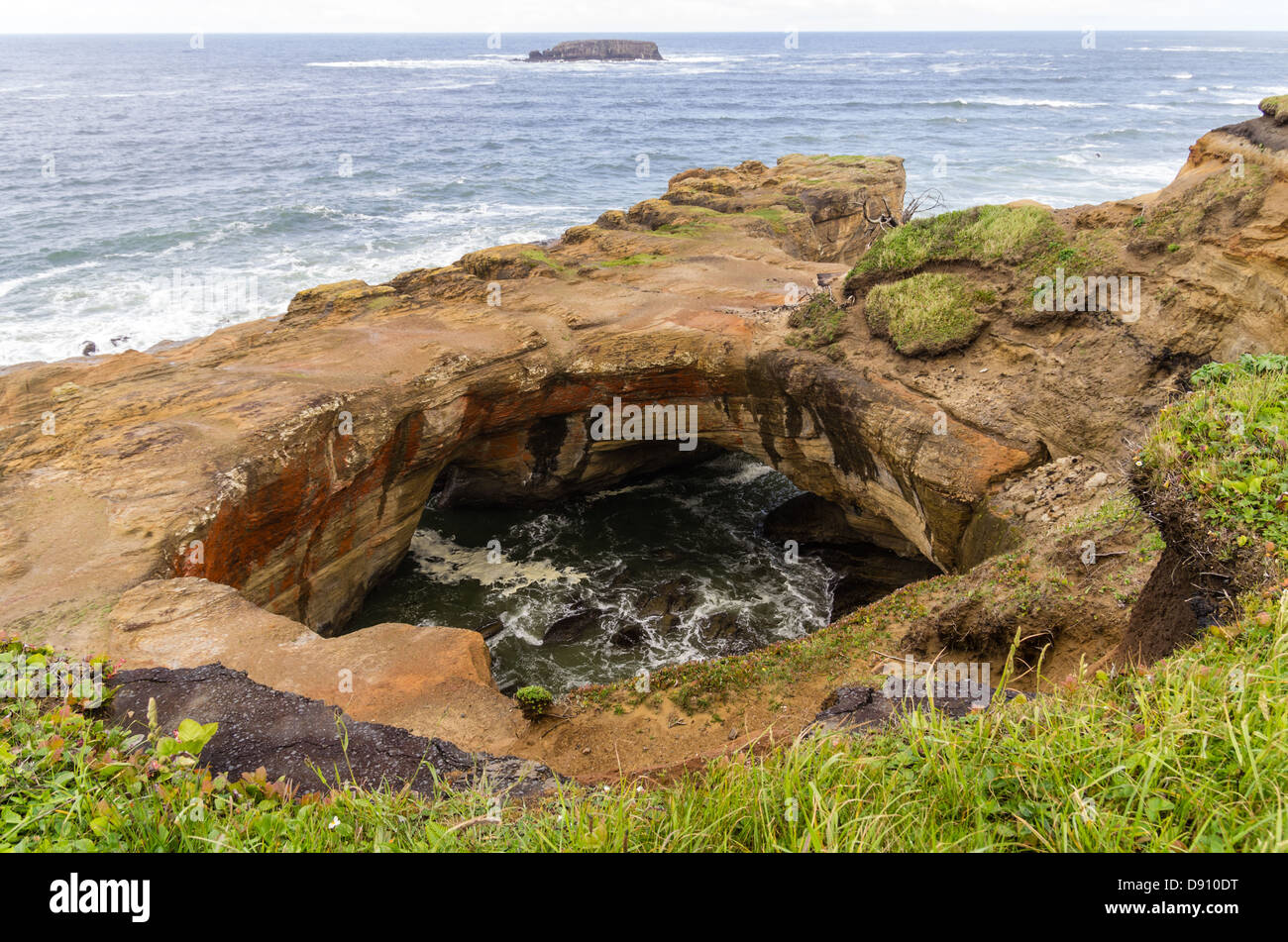 Oregon, Otter Rock, Devils Punch Bowl State Park. Water washes through Devil's Punchbowl rock formation Stock Photo