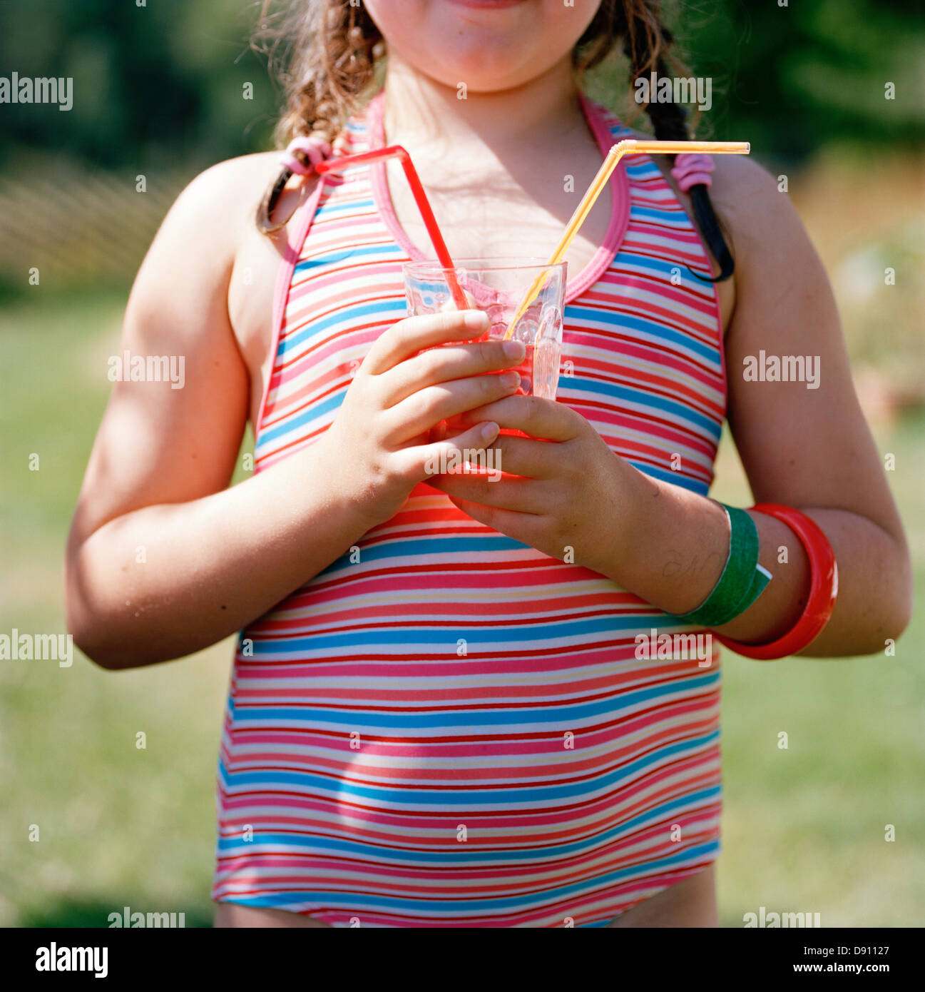 A girl holding a glas with straws in it, Sweden. Stock Photo