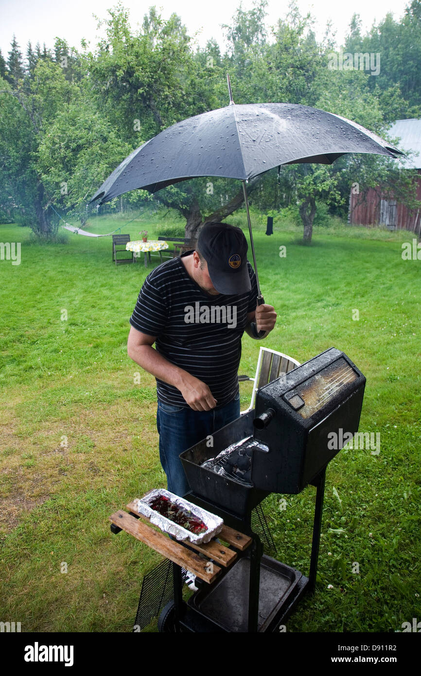 A man grilling in rainy weather, Sweden Stock Photo - Alamy