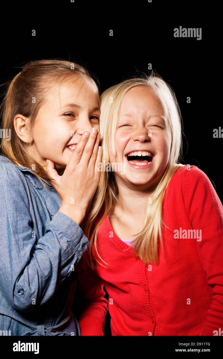 Studio shot of two girls whispering Stock Photo - Alamy