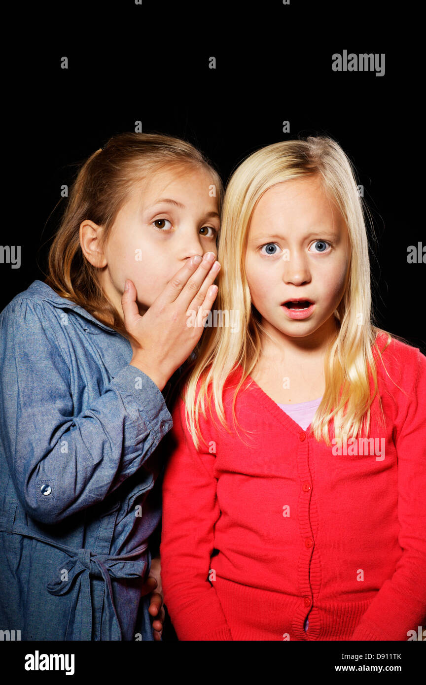 Studio shot of two girls whispering Stock Photo - Alamy