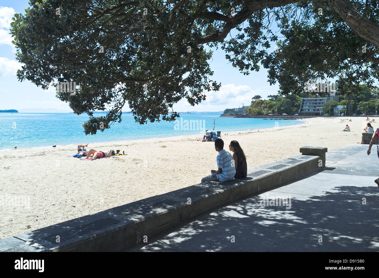 dh North island beaches AUCKLAND MISSION BAY NEW ZEALAND NZ Couple sitting on prome wall overlooking sandy beach nz people Stock Photo