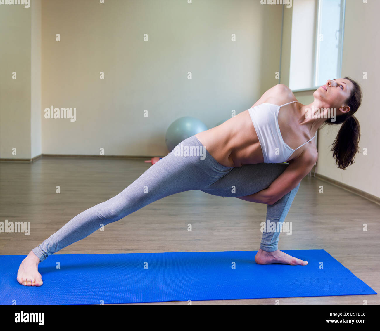 Pretty young woman doing yoga exercise on mat Stock Photo - Alamy