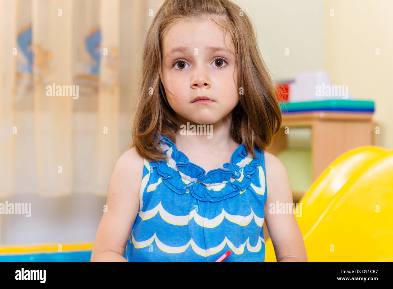 Portrait of cute serious little girl standing in playroom Stock Photo