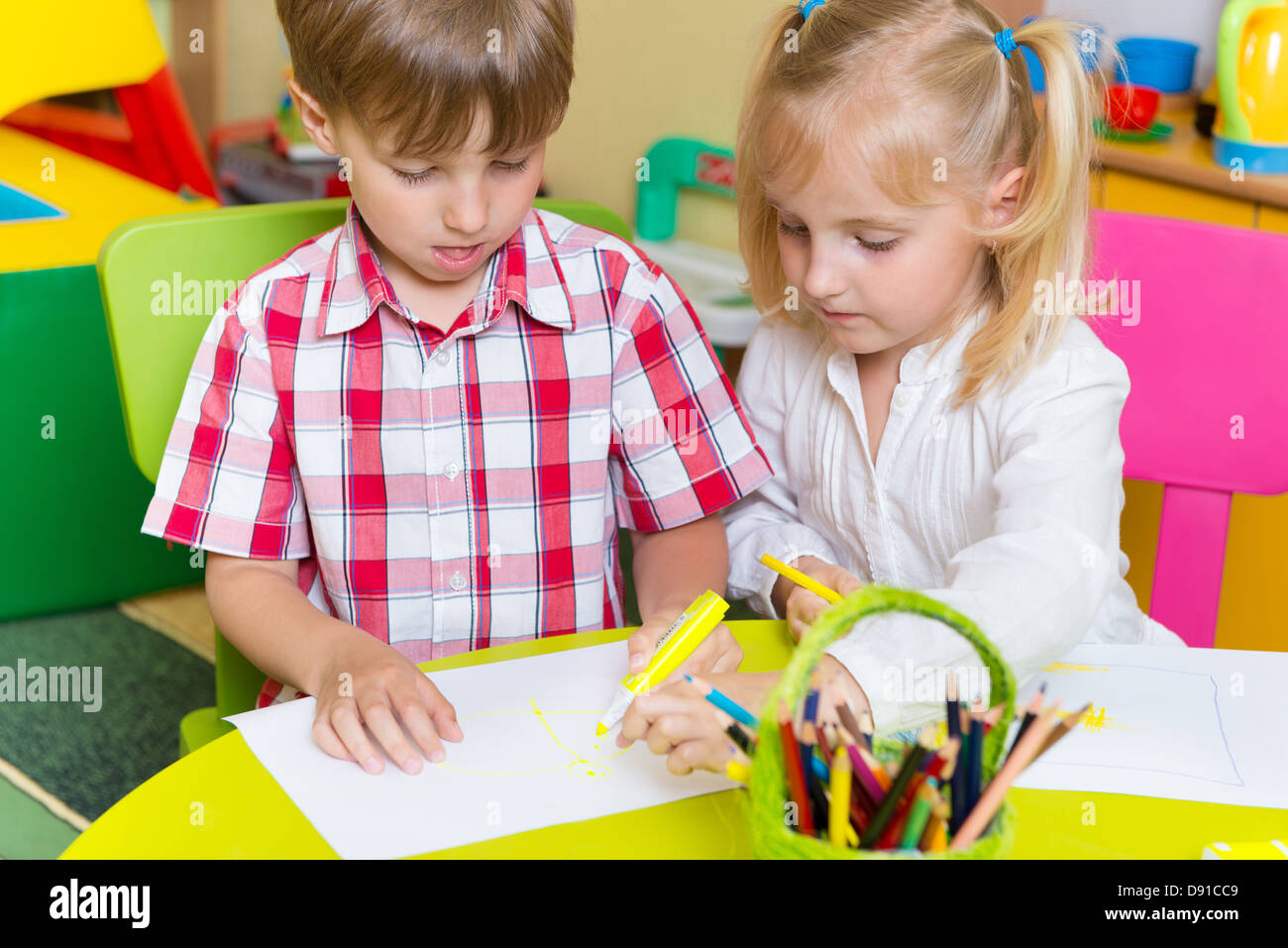 Two cute little prescool kids drawing with crayons at the table Stock ...