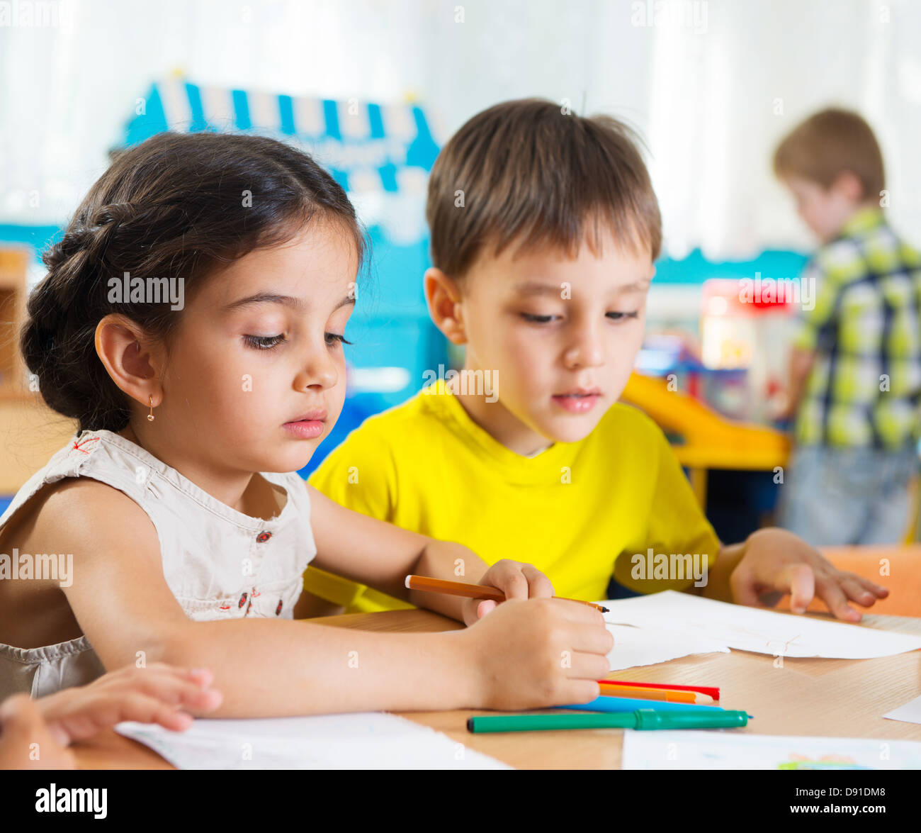 Cute preschoolers drawing with colorful pencils at daycare Stock Photo
