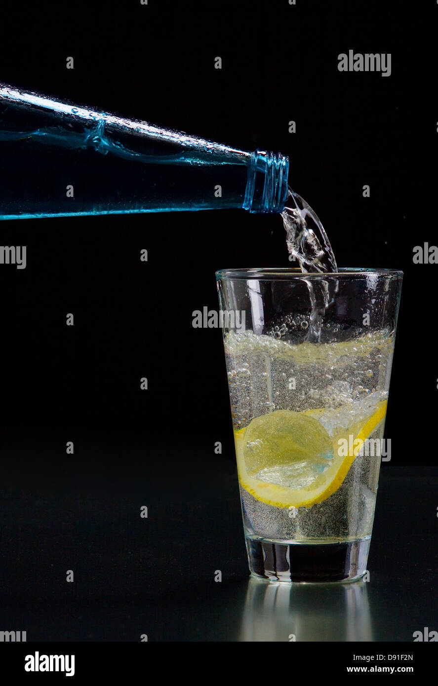 Mineral water is poured into a glass with ice and lemon Stock Photo - Alamy