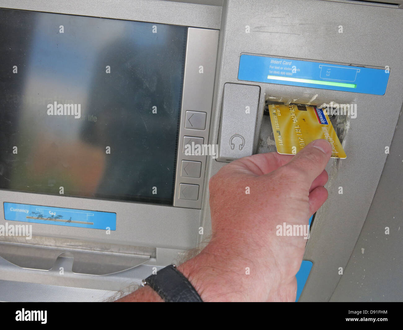 Putting a Nationwide account card into a co-op ATM cash machine yellow Stock Photo