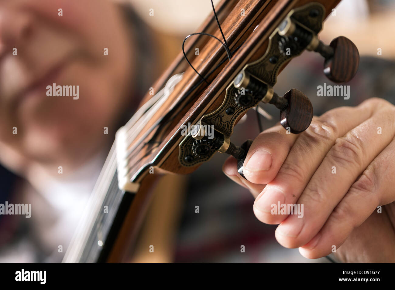 Close up of guitar maker tuning and testing acoustic guitar in