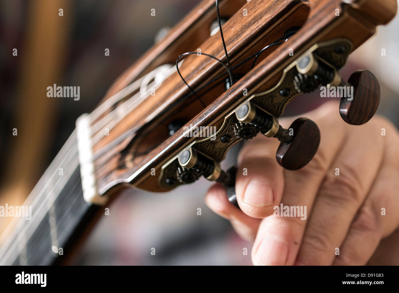 Close up of guitar maker tuning and testing acoustic guitar in