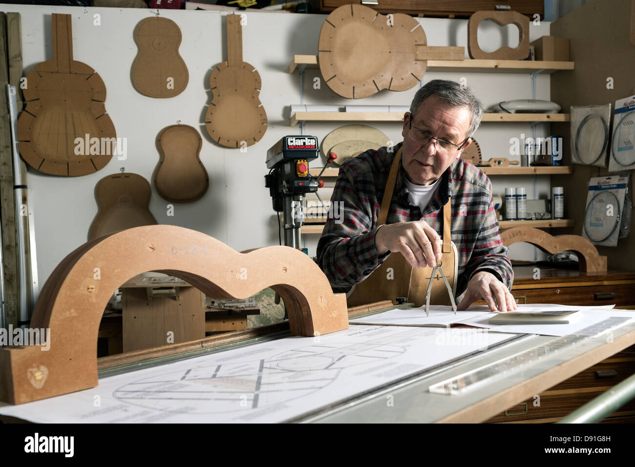 Guitar maker working on plans for an acoustic guitar in workshop Stock Photo