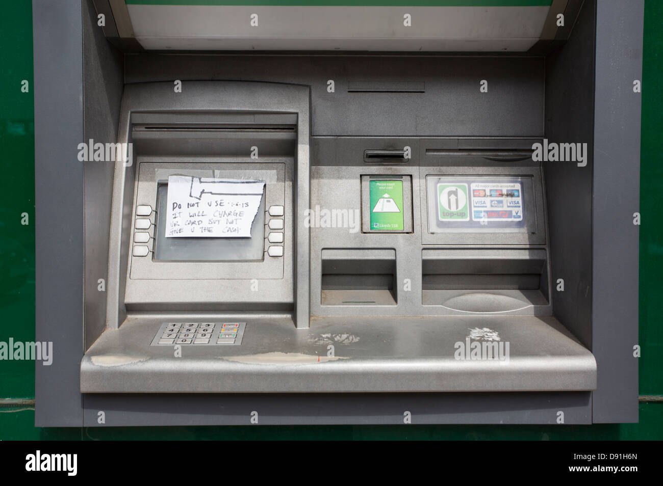 Out of order cash machine ATM with a hand written note covering the screen warning against using a bank card to withdraw money. Stock Photo