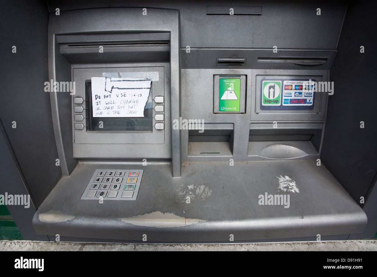 Out of order cash machine ATM with a hand written note covering the screen warning against using a bank card to withdraw money. Stock Photo