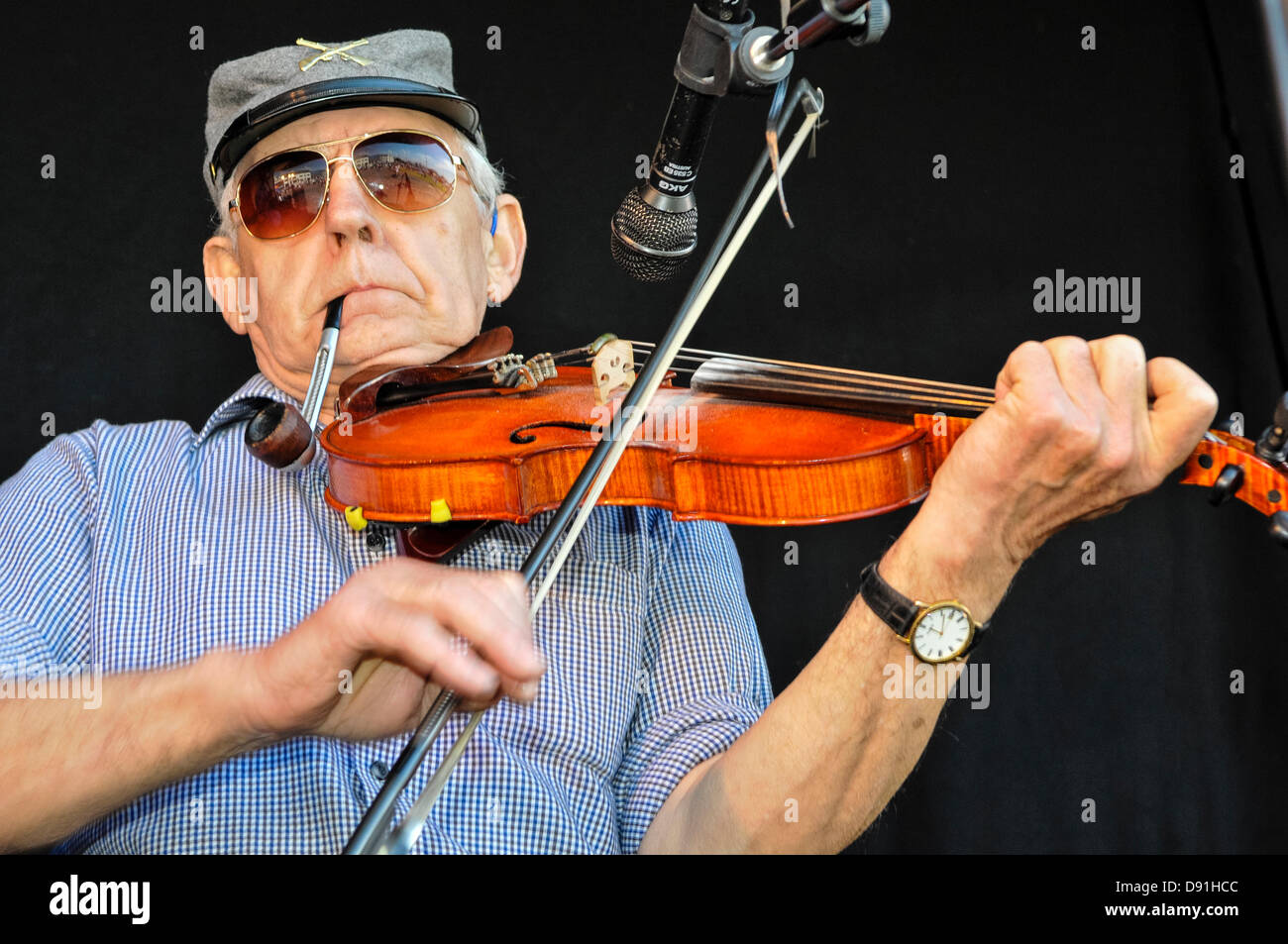 Carrickfergus, Northern Ireland. 8th June 2013. An elderly man smokes a pipe as he plays violin