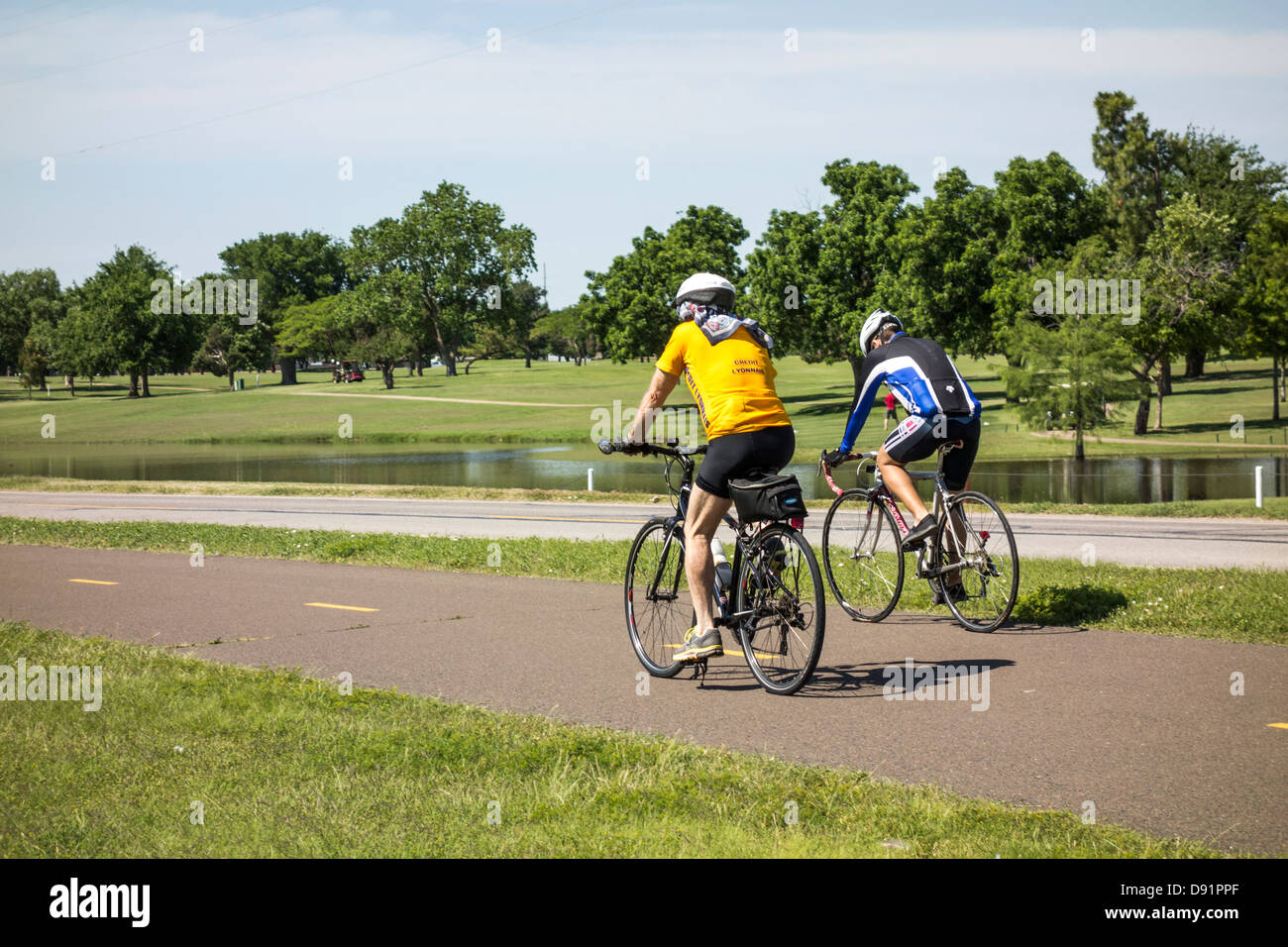 Two Caucasian men ride bicycles on the Lake Hefner trails in Oklahoma City, Oklahoma, USA. Stock Photo