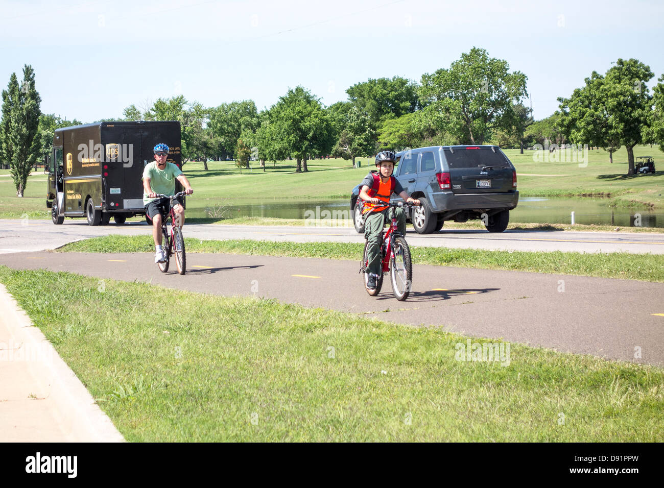 A Caucasian father and son ride their bicycles for exercise and pleasure on the Lake Hefner trails in Oklahoma City, Oklahoma, USA. Stock Photo