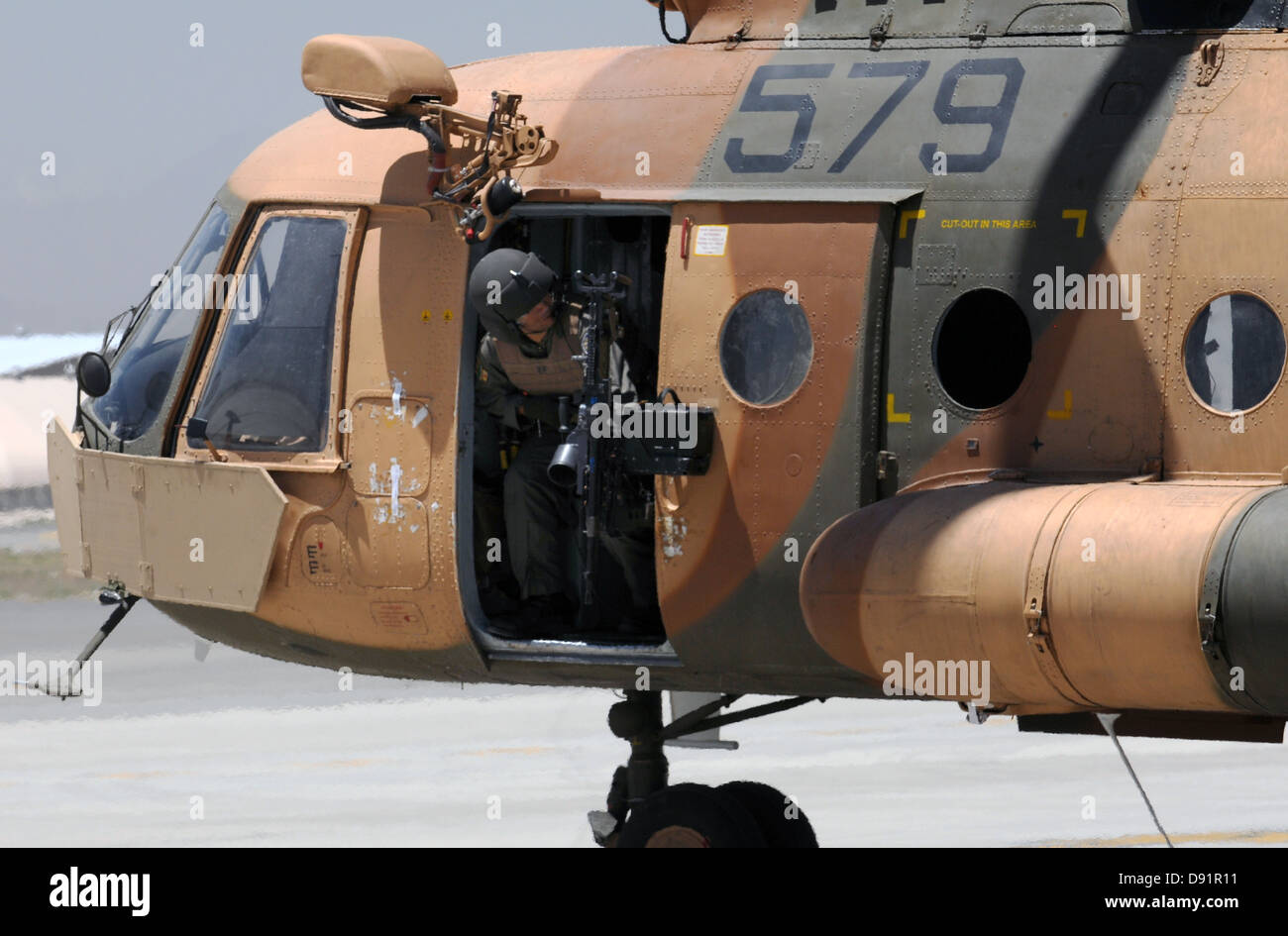 An Afghan Air Force aerial gunner clears the left side of his Mi-17 helicopter as they take off in a Mi-17 helicopter on an air assault mission May 29, 2013 at Kabul International Airport, Afghanistan. Stock Photo