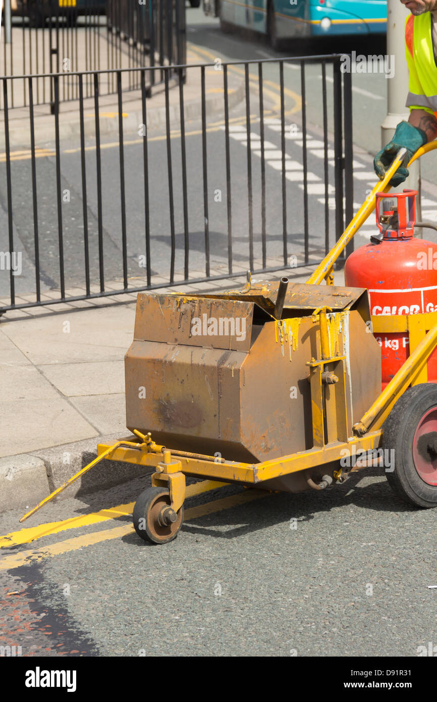 Double yellow line painting in progress. A Calor gas heater keeps