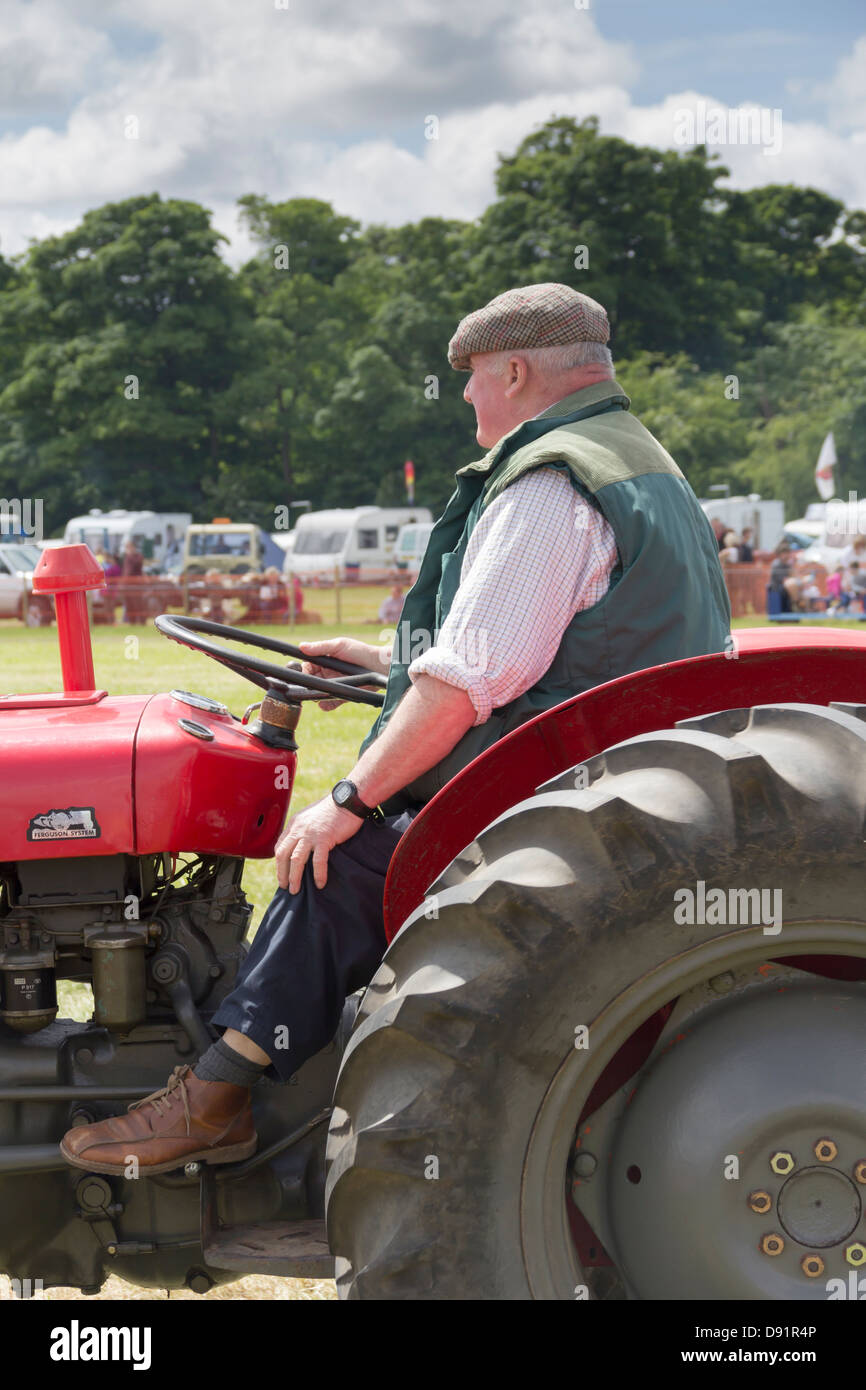 Mature man in traditional farming clothes driving a vintage Massey Ferguson tractor at Heskin Hall Steam Fair 2013. Stock Photo