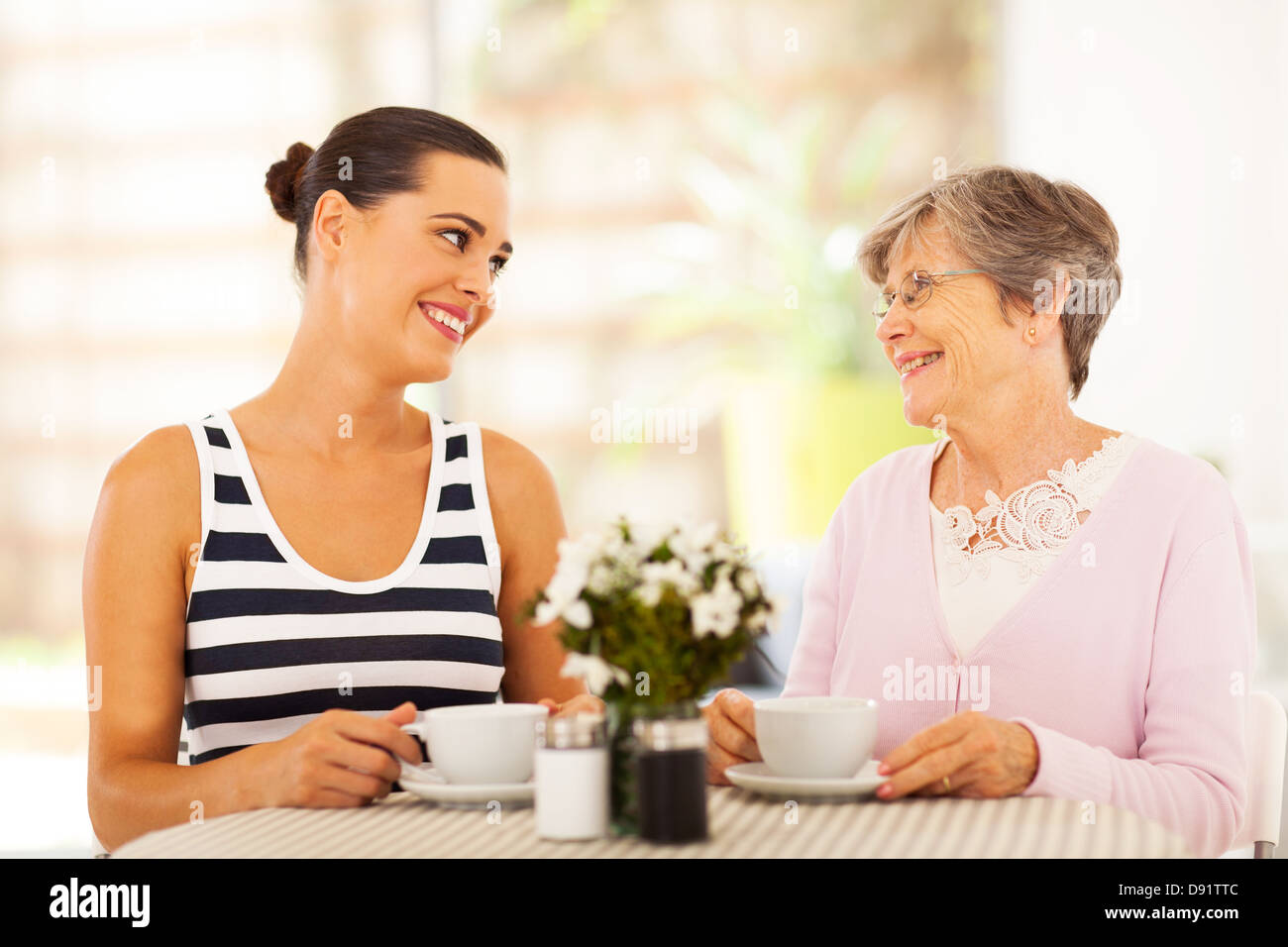 young woman visiting senior mother and having coffee together Stock Photo