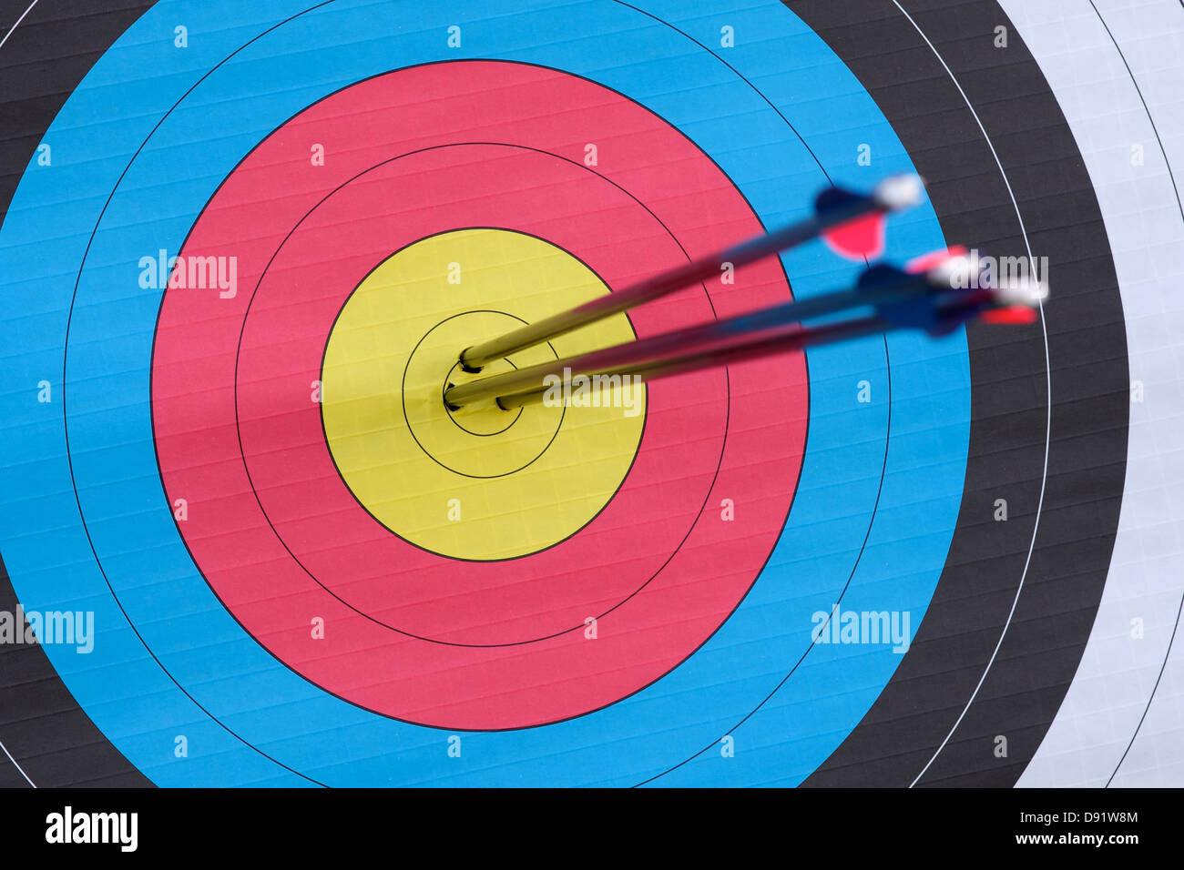 Three arrows embedded in the dead centre of an archery target Focus on