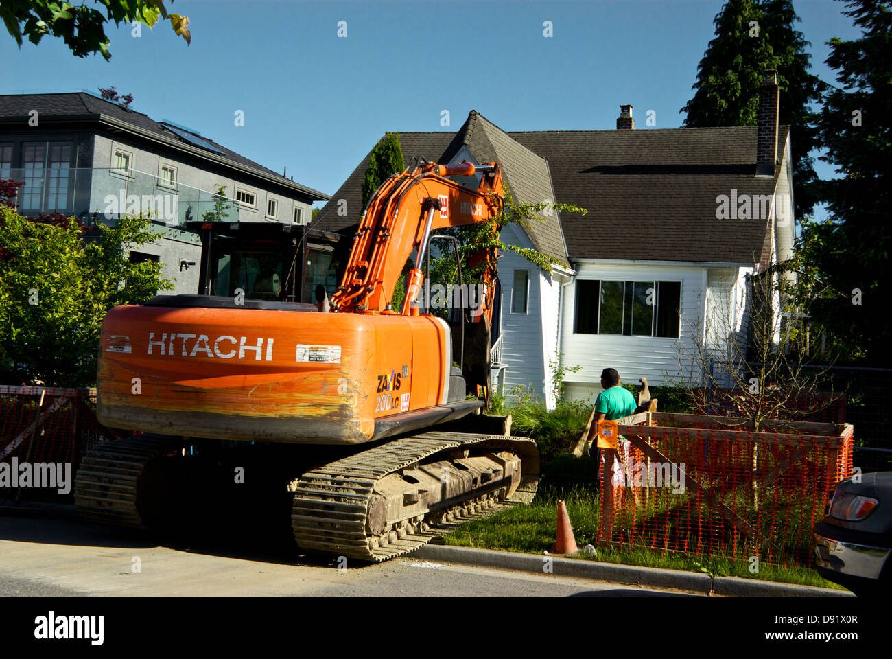 Hitachi Zaxis 200 LC excavator operator using hydraulic arm clamshell bucket to remove tree Vancouver house before demolition Stock Photo