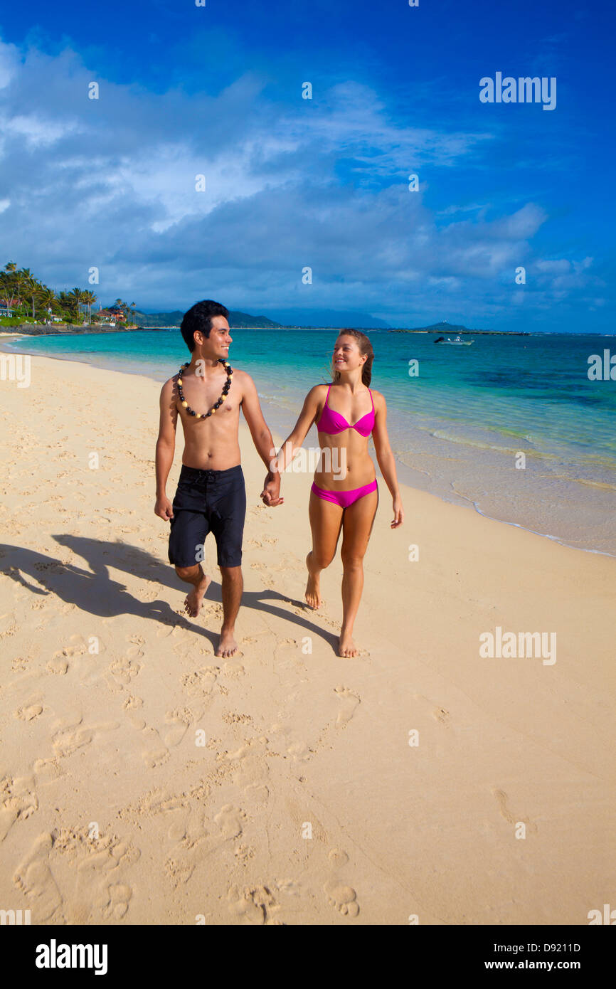 mixed couple walking on the beach in hawaii Stock Photo