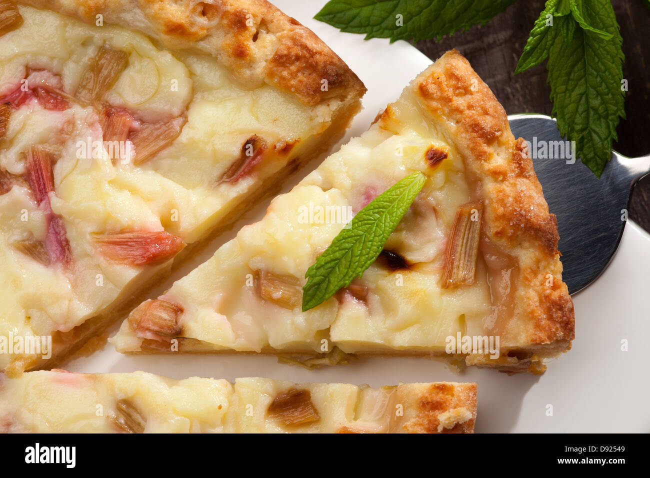 piece of tart with rhubarb and pudding, fresh green mint leaf Stock Photo