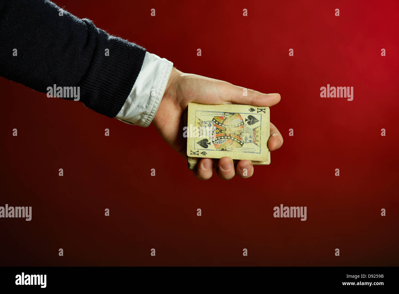 Male hand holding playing cards over red background. Stock Photo