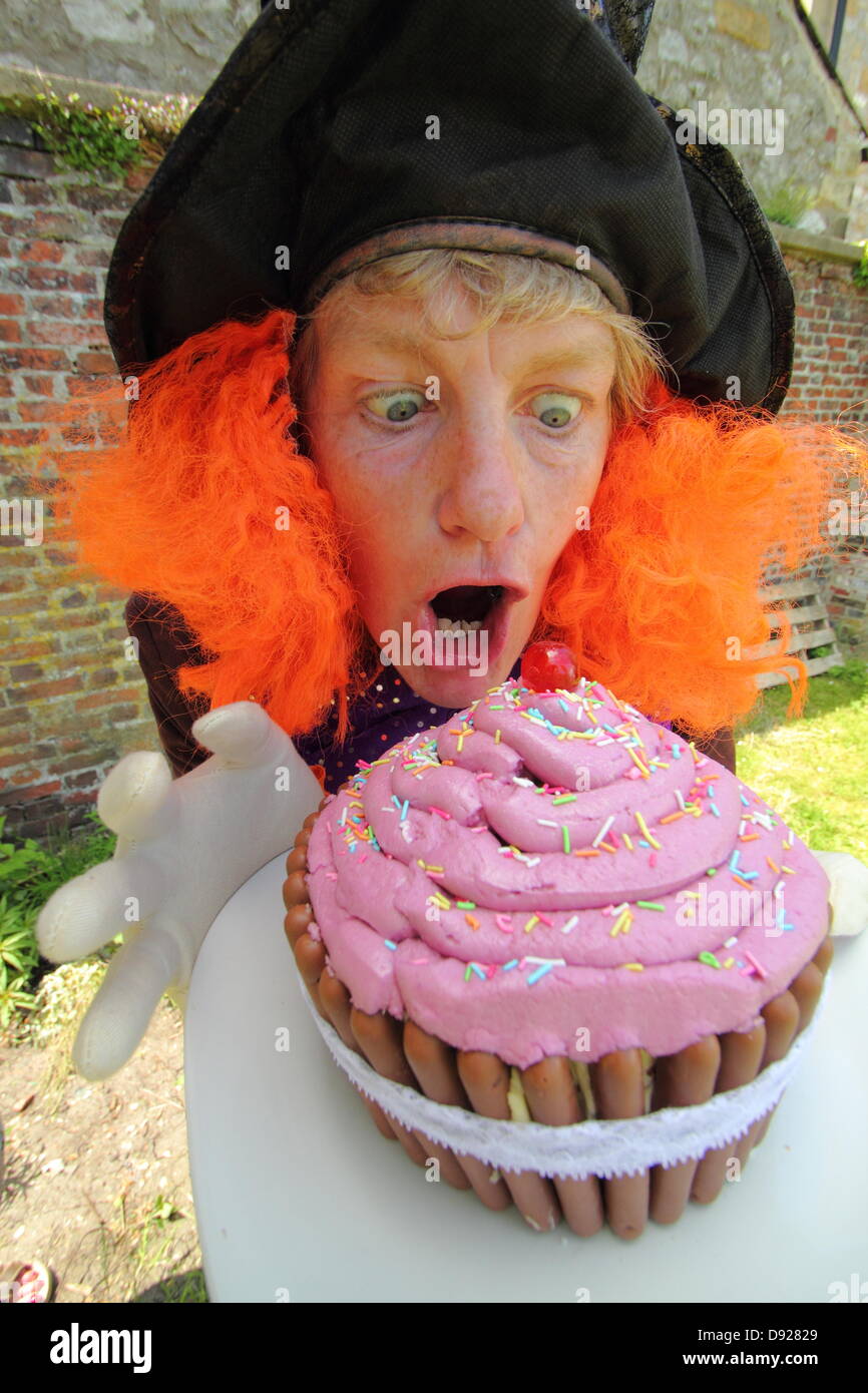 Bakewell, Derbyshire, UK. 9th June 2013. Bakewell Baking Festival. The Mad Hatter, Alison Benefield from Story Bag Theatre Company ditches tea for a giant cup-cake, Mad Hatter's Tea Party. Credit:  Deborah Vernon/Alamy Live News Stock Photo