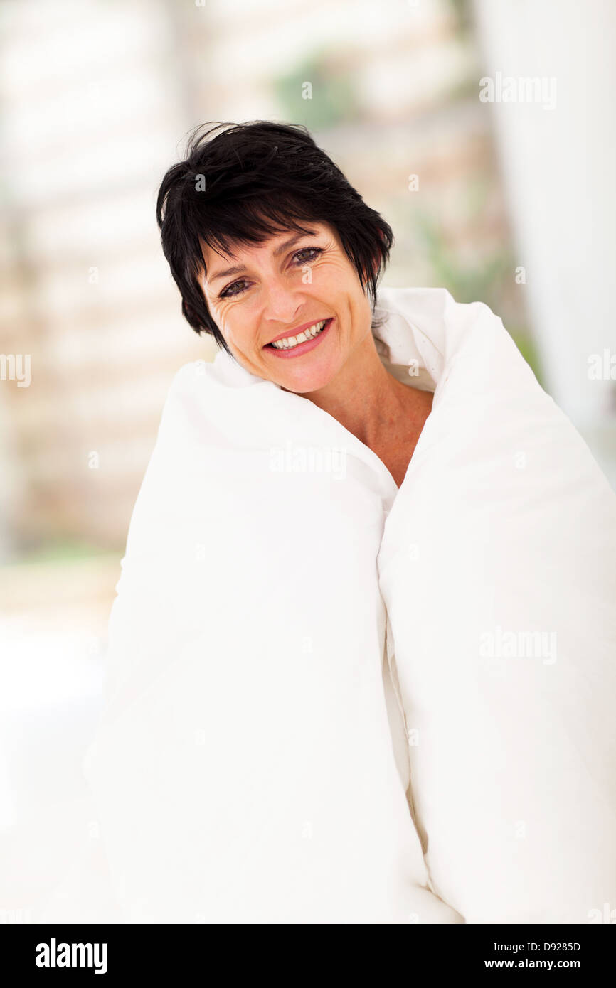 cute middle aged woman covered by duvet at home Stock Photo