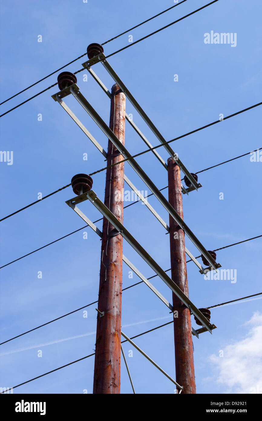 Wood post pylon supporting low voltage electricity transmission cables, blue sky Stock Photo