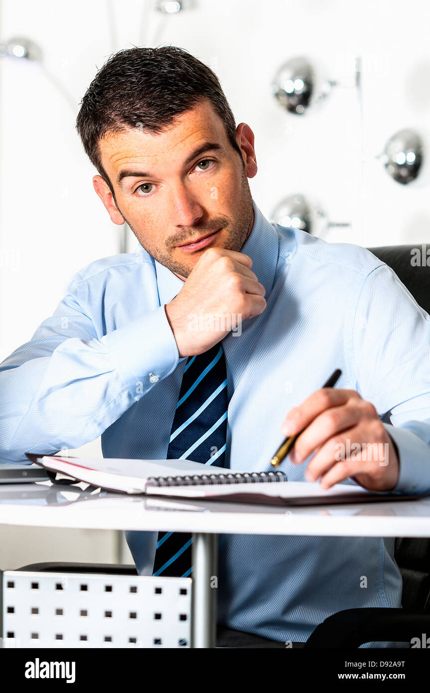 An attractive business man is writing on a paper Stock Photo - Alamy