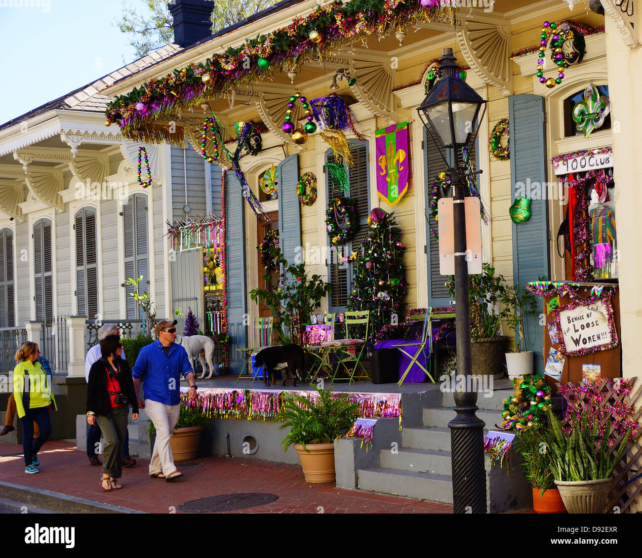 Tourists pass by a home decorated for Mardi Gras in New Orleans Stock Photo