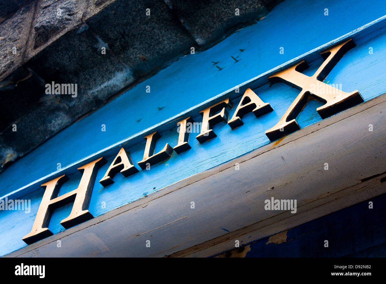 Large sign reading 'Halifax' in serif gold 3D lettering on blue wood wall seen from below in downtown Halifax, Nova Scotia Stock Photo