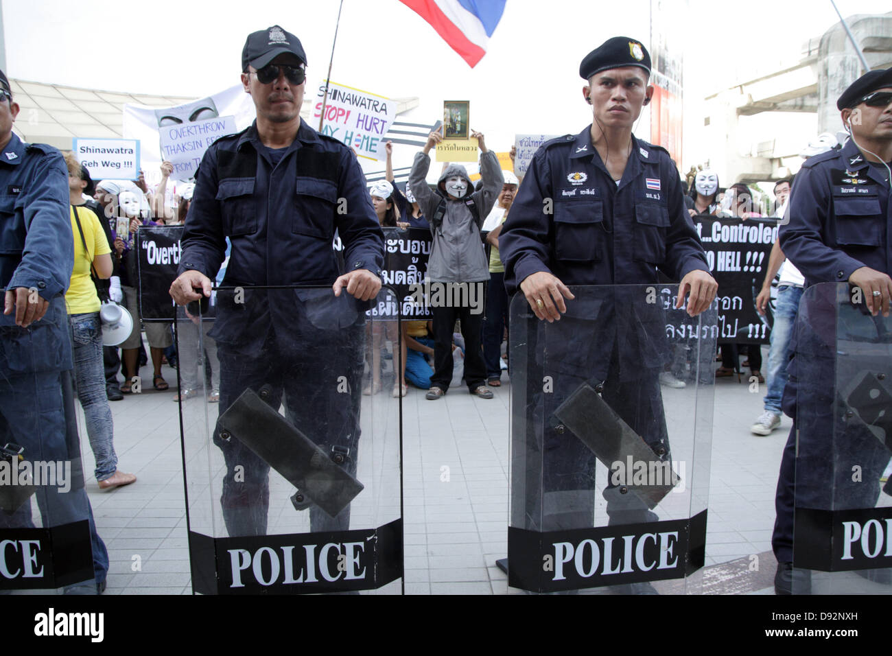Bangkok , Thailand. 9th June 2013. Guy Falkes white mask protesters during protest behind a riot policeman at The Bangkok Art and Culture Centre. Protesters wearing "Guy Fawkes" continue to rally in Bangkok and others parts of Thailand against the Yingluck Shinawatra government, which opponents say is a "puppet" regime controlled by fugitive former premier Thaksin Shinawatra. Credit:  John Vincent/17�Թ����� Live News Stock Photo