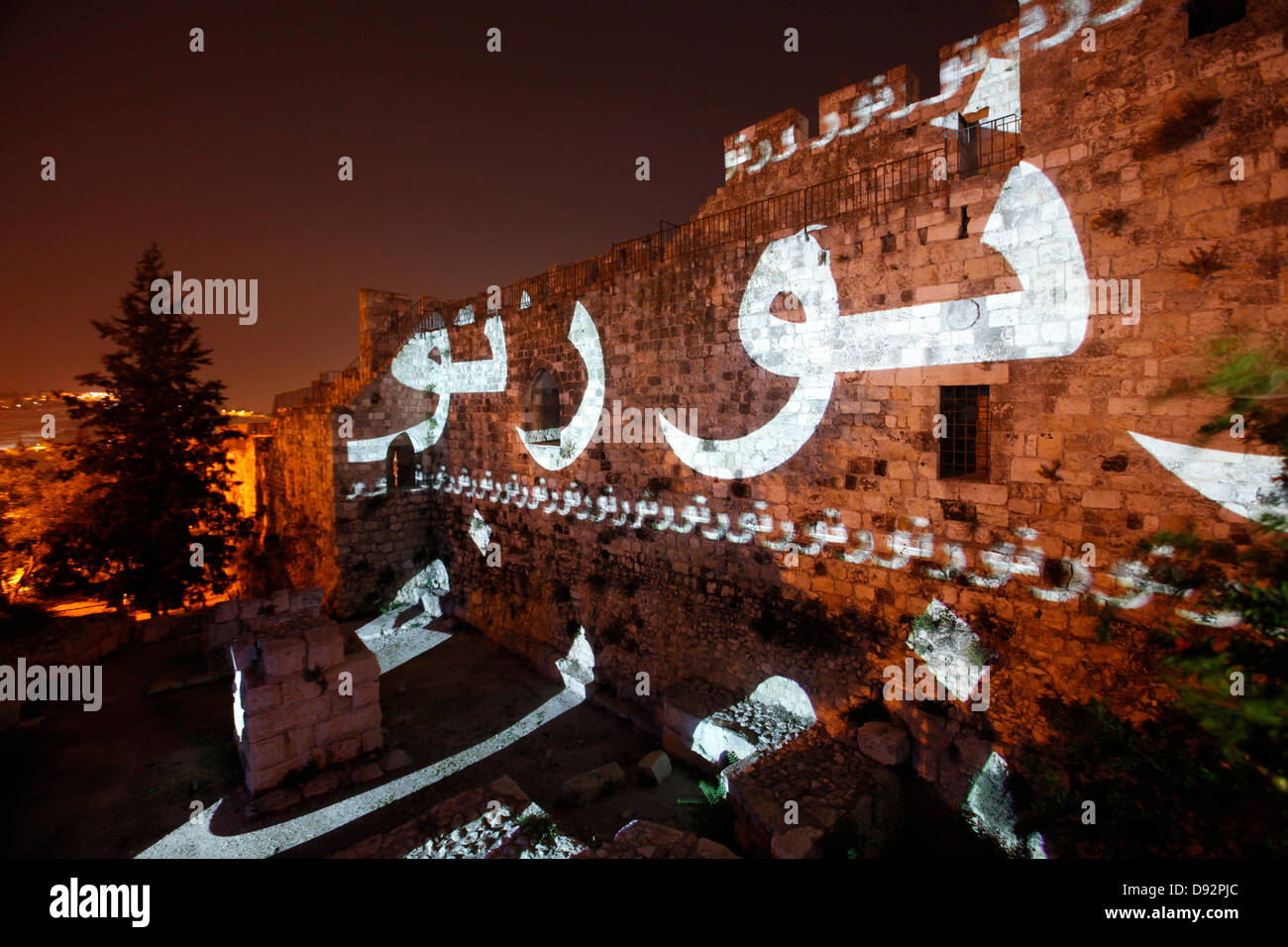 The word Light in Arabic is projected onto the Ottoman walls surrounding southern edge of the old city during the Jerusalem Festival of Light in Israel which takes place annually around the old city with special effects illuminating historical sites and displays the work of leading international artists. Stock Photo