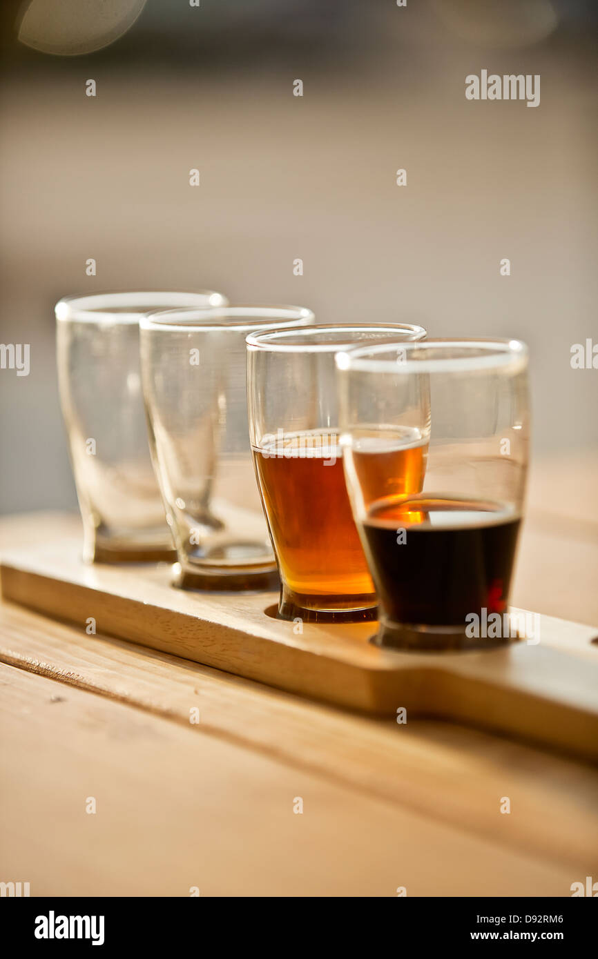 Close up of beer sample glasses on a wooden paddle, outdoors. Stock Photo