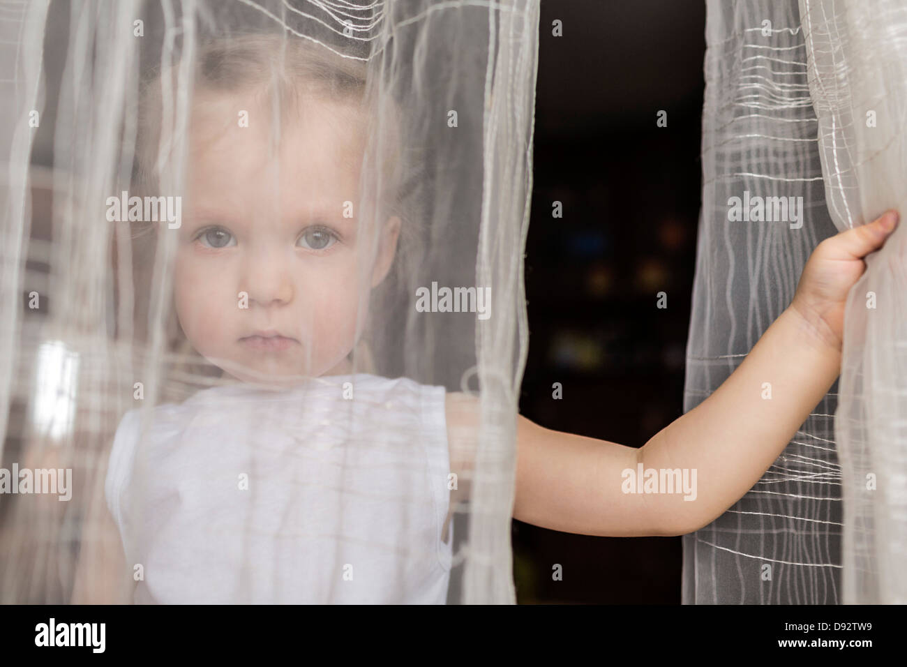Girl staring behind translucent curtains Stock Photo