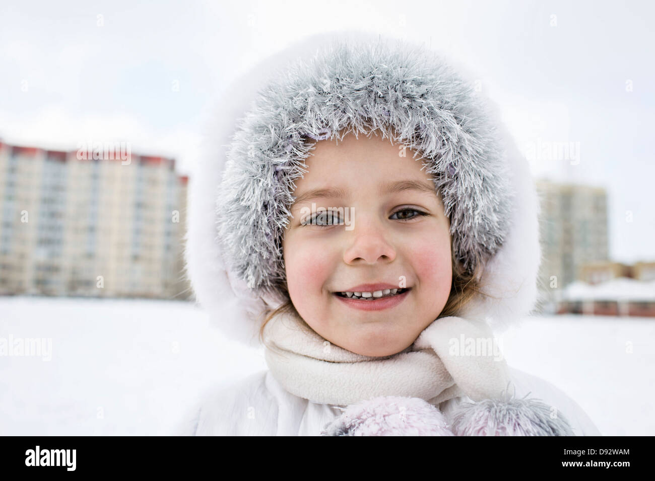 A cheerful young girl wearing warm clothing outdoors in winter Stock Photo