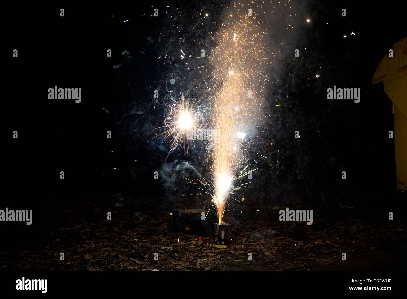 Sparks and smoke coming out of a firework exploding on a sidewalk Stock Photo