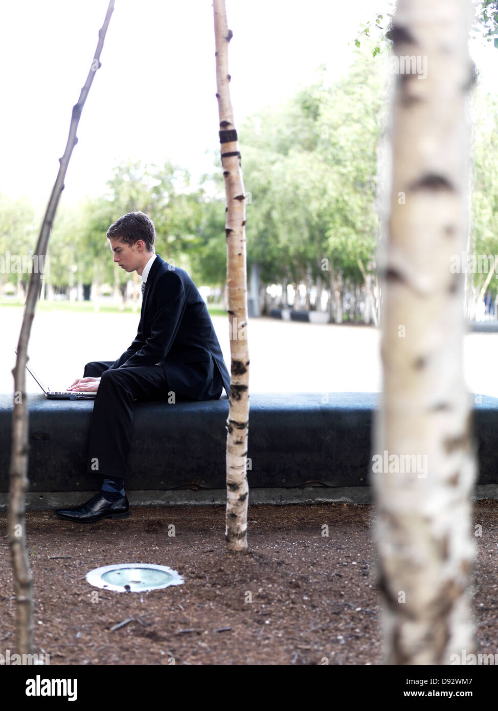 A young businessman using a laptop at a city park Stock Photo - Alamy